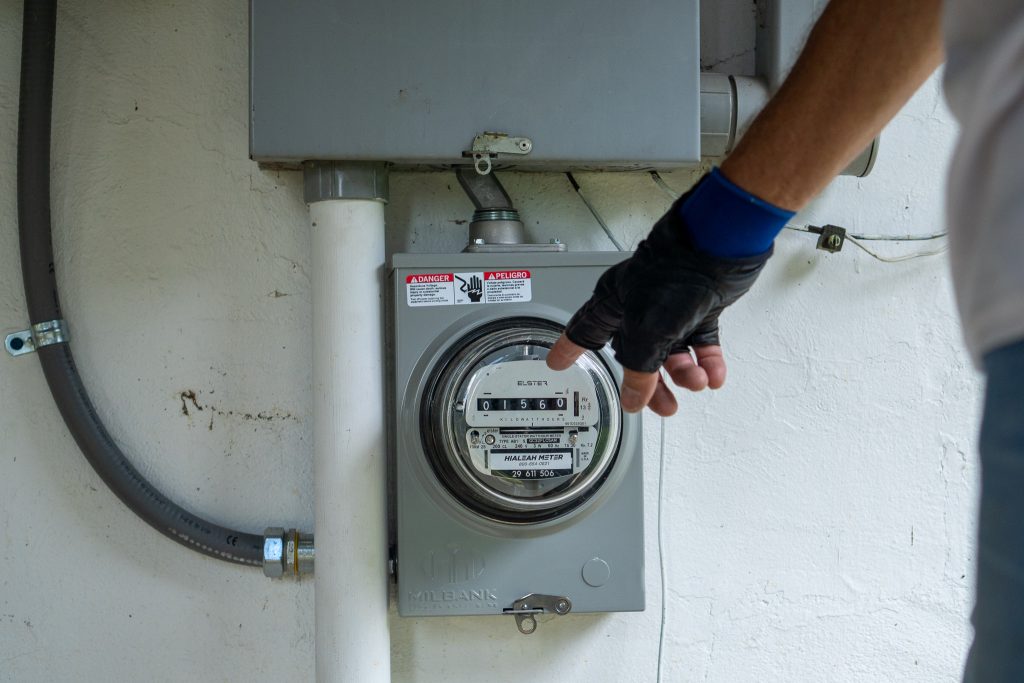 Man pointing at a production meter on a solar array.